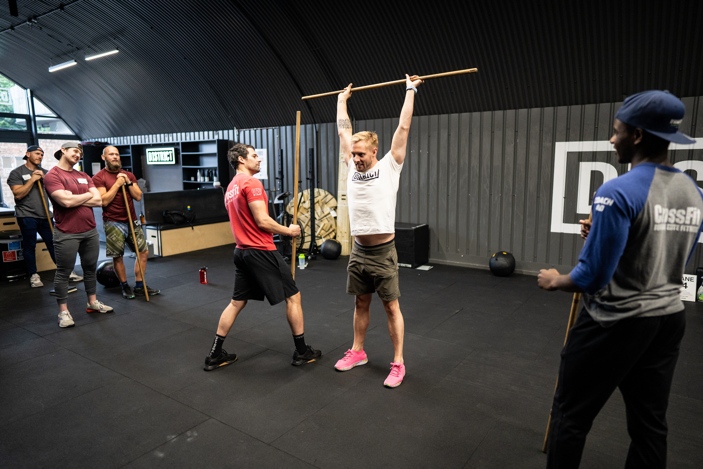 A CrossFit Seminar Staff Trainer coaches an athlete on the shoulder press.