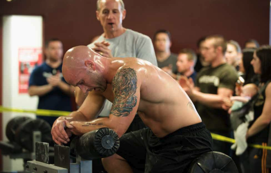A sweaty man rests on the GHD machine.