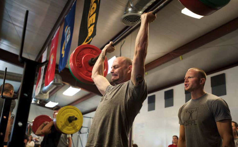 A man struggles to press a barbell overhead.
