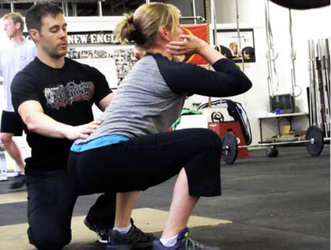 A coach works with an athlete on the front squat.