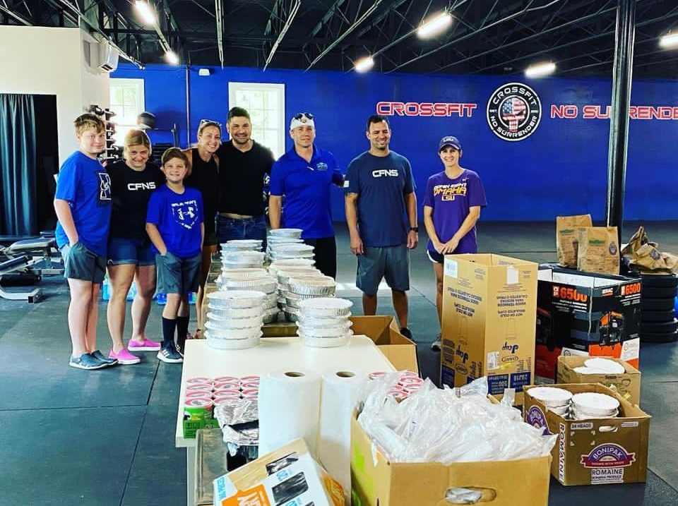 The community at CrossFit No Surrender gathers around donated food, toiletries, and other items. 