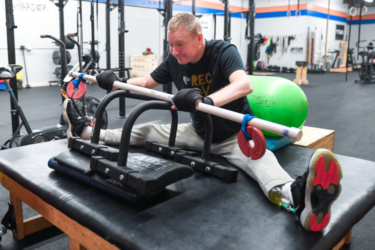 Joe Hennen performs seated rows with a weighted PVC pipe.