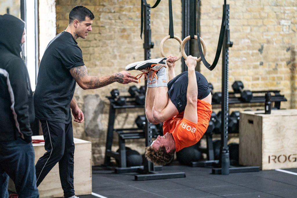 An athlete practices gymnastics on rings in a CrossFit gym