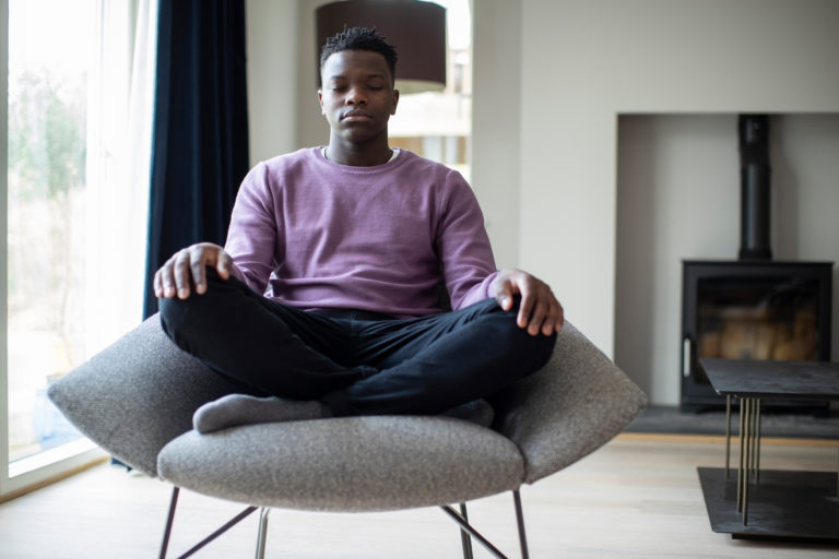 A boy meditates in a comfortable chair