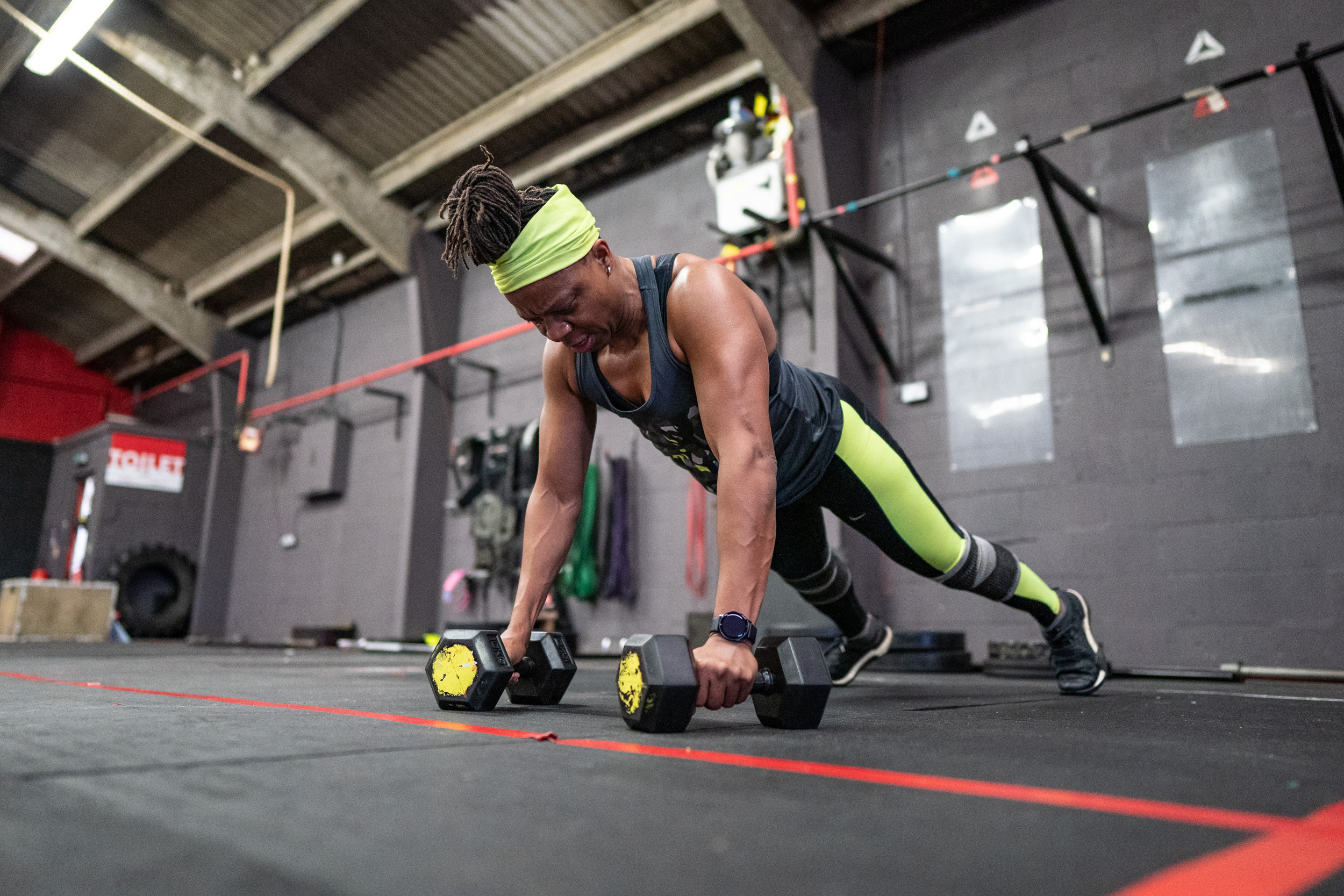 Woman holding plank on dumbbells