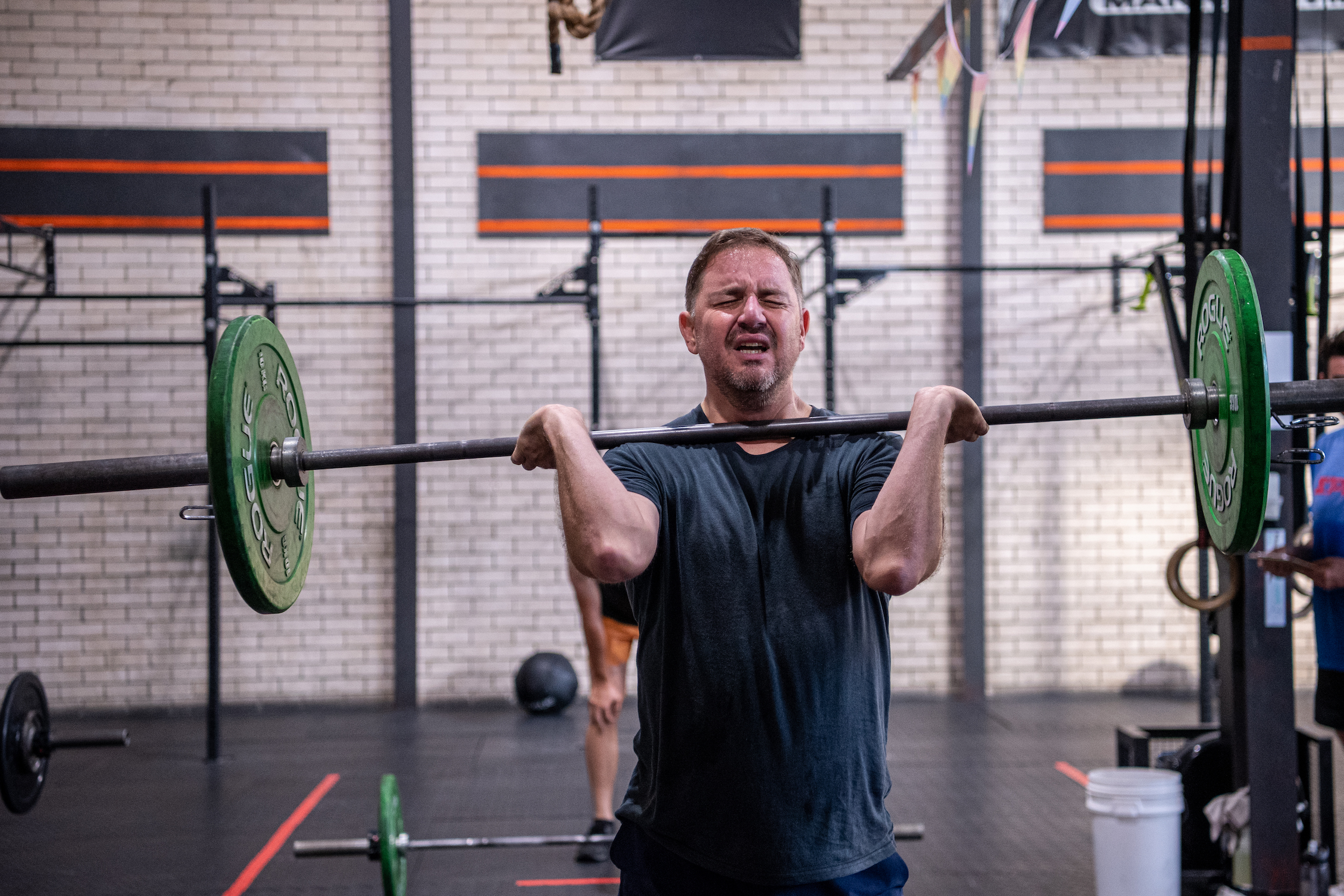 A man grimaces as he completes a barbell clean