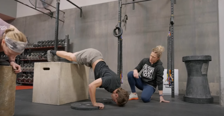Nicole Christensen coaches an athlete doing pike push-ups from a box.